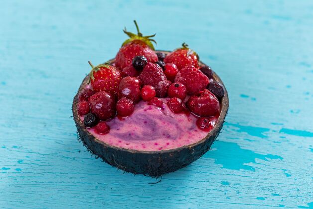 甜点特写镜头的水果奶昔顶部冷冻草莓 红莓在椰子碗美味浆果多汁