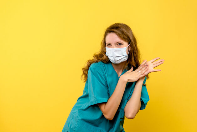 人黄色空间里戴着面具的女医生的正视图冠状病毒正面成人