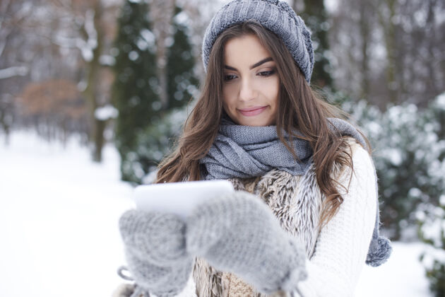 寒冷冬日里拿着手机的年轻女子手套冬天年轻
