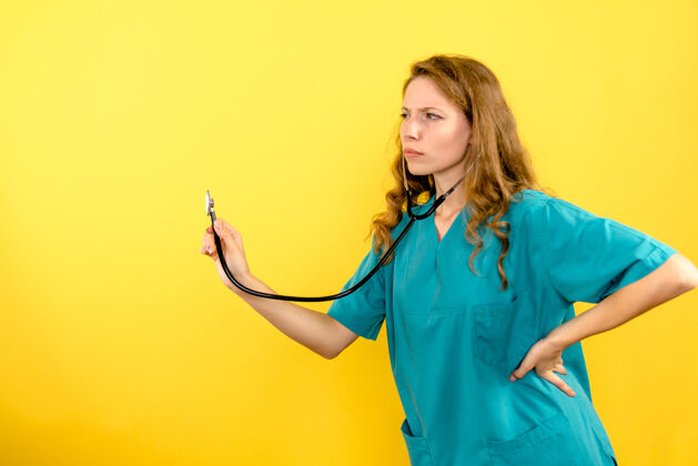 护理前视图女医生用听诊器对黄地板病毒健康冠状病毒大流行制服冠状病毒人