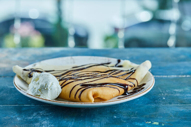 鞭子薄煎饼配香草冰淇淋 巧克力放在蓝色的白色盘子里薄煎饼吃的食物