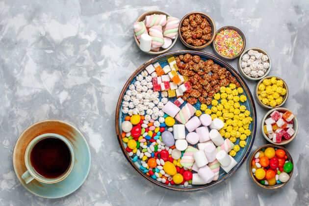 膳食顶视图糖果组成不同颜色的糖果与棉花糖内锅与茶上的白色办公桌糖糖果邦邦甜蜜的封视图生的食物