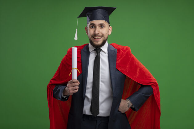 拿着毕业的红衣人拿着毕业证书站在绿色的墙边快乐而欢快的微笑证书毕业欢呼