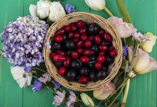 景观顶视图的水果 如树莓和山茱萸浆果在篮子里与周围的鲜花绿色背景水果花顶部