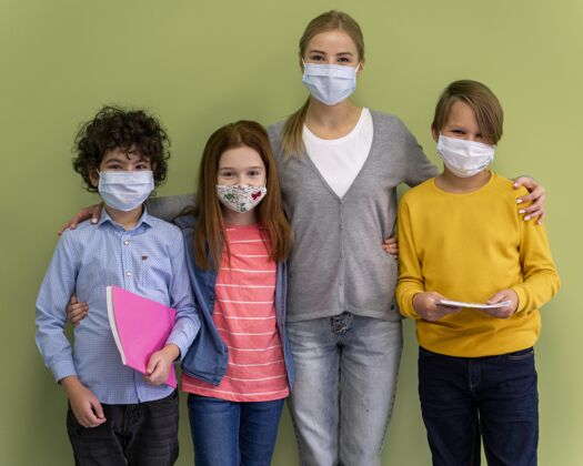 教师戴着医用口罩的女老师在学校和孩子们合影课堂新常态教育