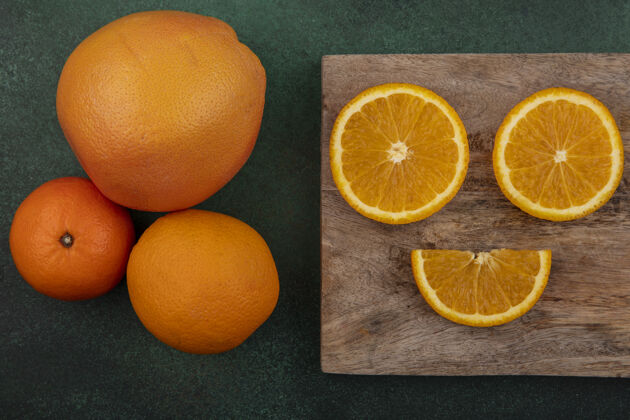 橘子俯视图切割板上的橙色切片和绿色背景上的葡萄柚水果新鲜视野