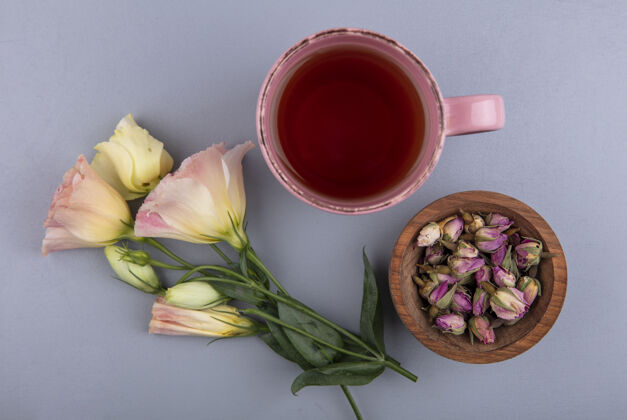 茶顶视图新鲜的玫瑰芽在一个木碗与一杯茶的灰色背景碗景观顶部