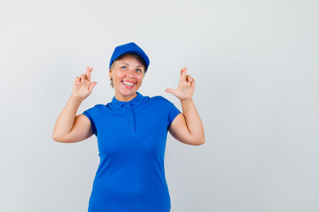 肖像成熟的女人穿着蓝色t恤 双手交叉 看起来很快乐帽子脸女士