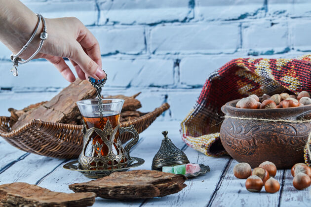 木头女人的手拿着一勺茶和各种糖果放在蓝色的木桌上碗桌子勺子