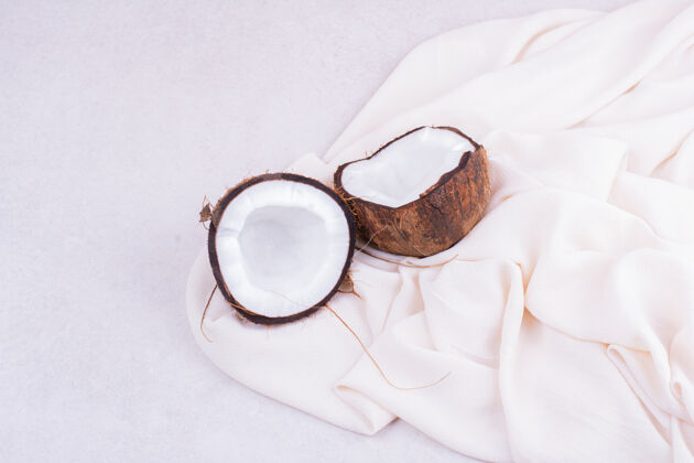极简一个棕色的椰子在白毛巾上切成两块乳白色产品水果