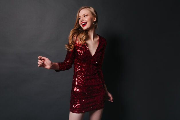 人一位身着红色礼服的年轻女子在派对上翩翩起舞 在摄影棚拍摄了一张幸福的金发女孩在深色背景下的合影成人奢华魅力