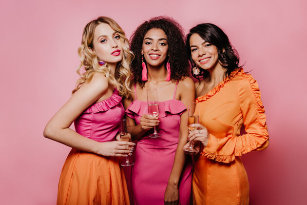 女性漂亮的女人在粉红色的墙上喝香槟生日美好时光酒精
