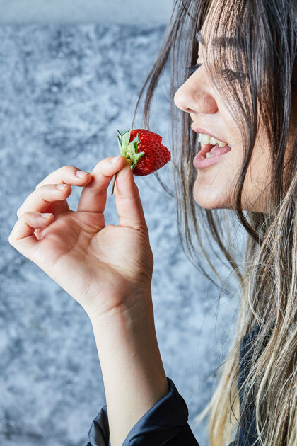 夏天在大理石表面吃新鲜红草莓的女人女人美味切片