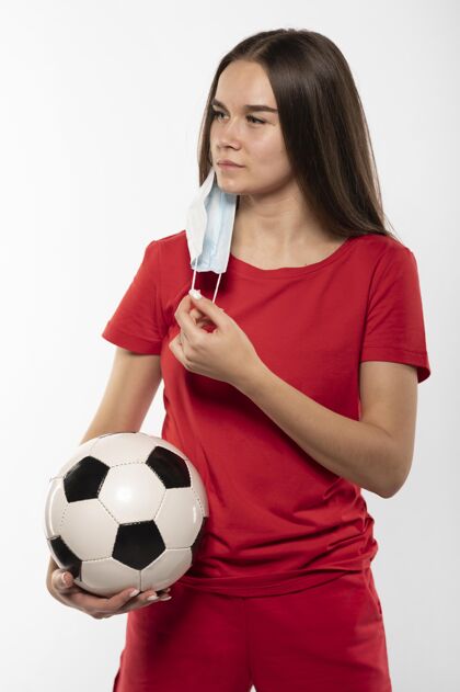 持球戴着面具拿着球的女足球运动员女足球运动