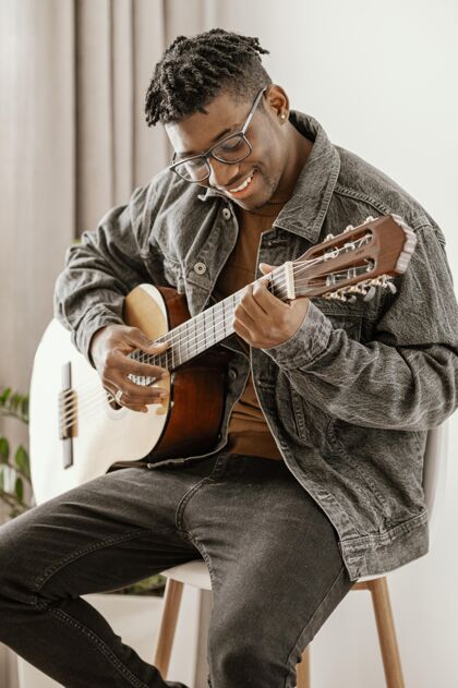 技能笑脸男音乐家在家弹吉他的正面图乐器手熟练程度人才
