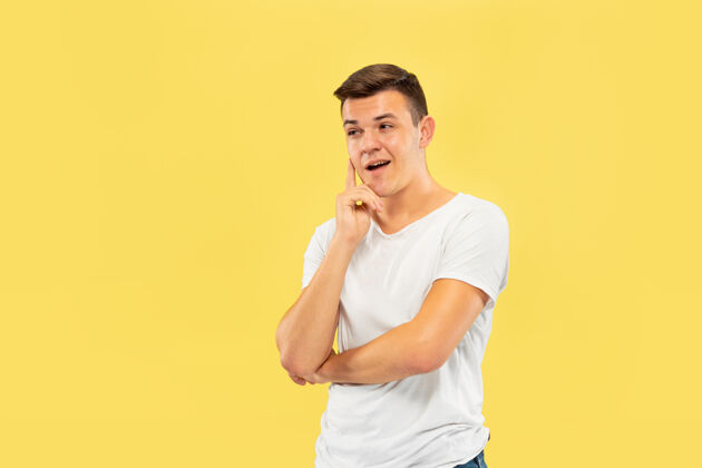 工作黄色工作室背景上的白人年轻人半身肖像穿着衬衫的漂亮男模人类情感的概念 面部表情 销售 广告思考 有想法 参加高管事业表情