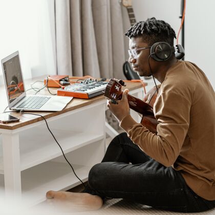 房子男音乐家在家里弹吉他和笔记本电脑混音技能广场创意