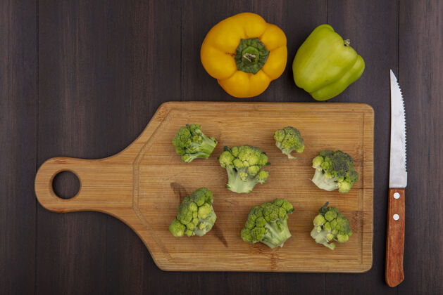 胡椒顶视图彩色甜椒与西兰花切菜板与刀在木制背景新鲜木材花椰菜