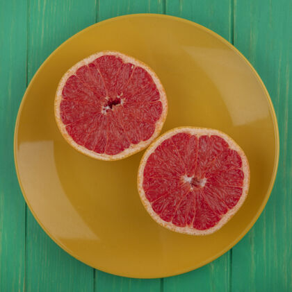 水果在绿色背景的黄色盘子上俯视葡萄柚的一半盘子视野绿色