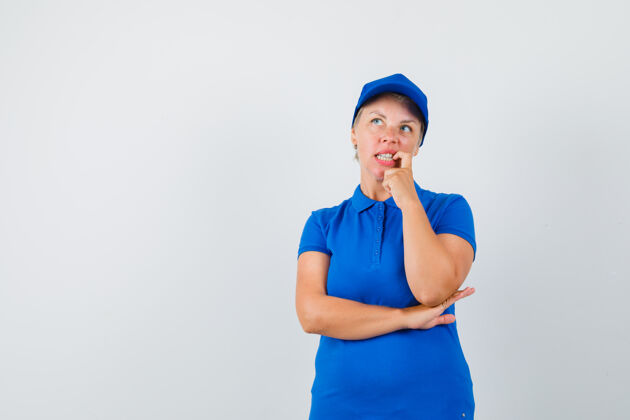 女人成熟的女人穿着蓝色t恤站在思考的姿势 看起来很犹豫思考人蓝色