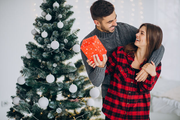 圣诞灯年轻夫妇一起在家里的圣诞树旁浪漫圣诞装饰帅哥