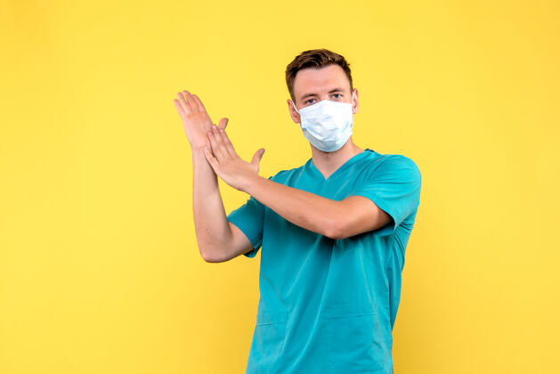 医学黄色墙上戴着口罩的男医生的正视图前面男医生快乐