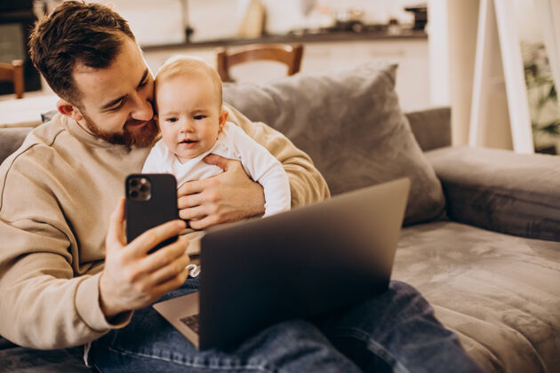 小玩意年轻的父亲和他的女婴坐在一起 在家里用电脑儿童成人设备