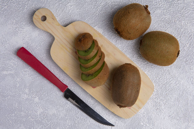 水果用白色背景上的刀在砧板上俯瞰猕猴桃观点刀猕猴桃