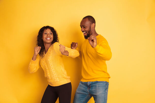 女性年轻感性的非裔美国人 穿着黄色背景的明亮休闲服美丽的情侣人类情感的概念 面部表情 关系 广告跳舞和唱歌化妆品时尚微笑