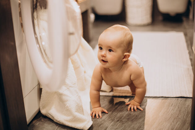帮助可爱的婴儿在洗衣机旁蹒跚学步的女孩小洗衣机可爱的女婴