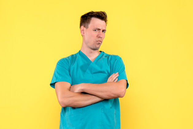 医院黄色墙壁上的男医生的前视图 带着不满的表情人正面成人