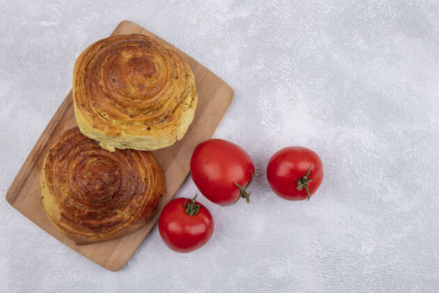 空间阿塞拜疆传统糕点gogal的顶视图 木质厨房板上有新鲜西红柿 白色背景上有复制空间新鲜木材糕点