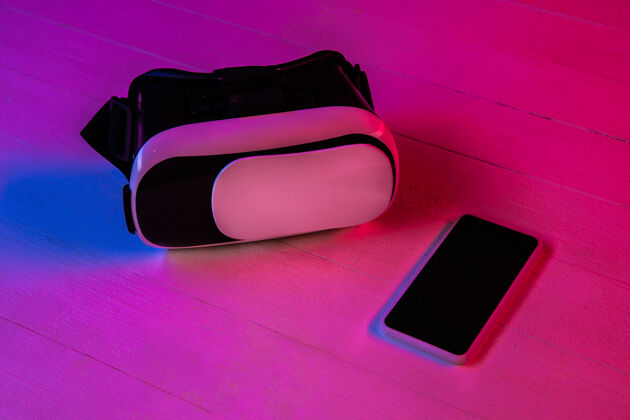 技术紫色霓虹灯和粉色背景的一组小玩意的俯视图智能手机和vr耳机广告的复制空间科技 现代 小玩意虚拟现实网络电话明亮