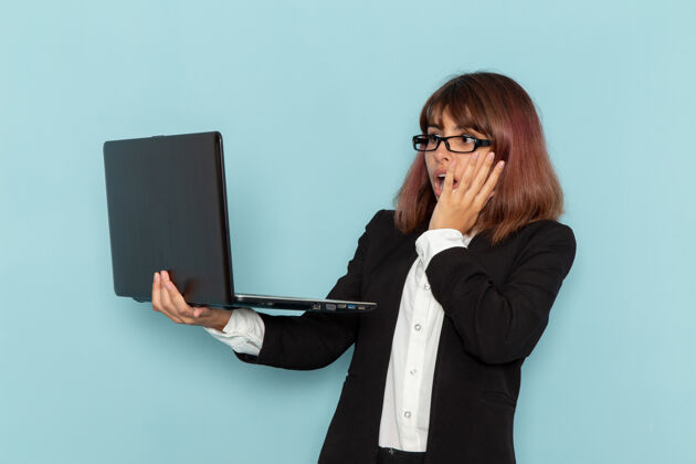 工作正面图：穿着正装的女上班族 使用笔记本电脑 浅蓝色表面上有震惊的表情西装公司正面