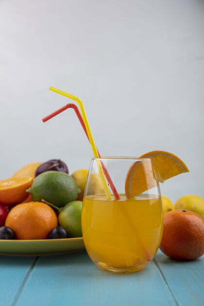 盘子前视图橙汁在一个玻璃杯里 樱桃李子橙子李子柠檬和柠檬放在一个黄色的盘子里酸橙玻璃杯李子