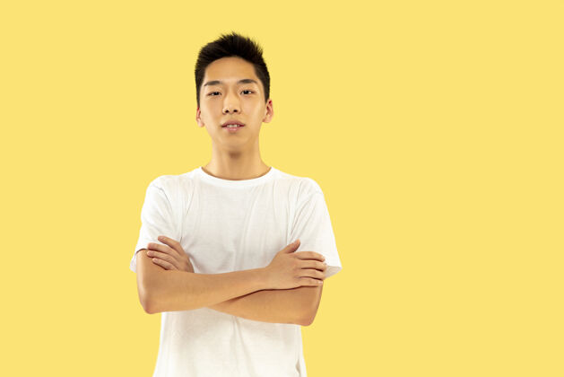 公司黄色工作室背景上的韩国年轻人半身像穿白衬衫的男模站着看人类情感的概念 面部表情正面视图流行的颜色男人员工工作
