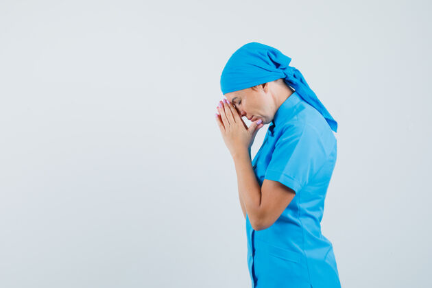 成人身穿蓝色制服的女医生手牵手祈祷 看上去充满希望祈祷女人疾病