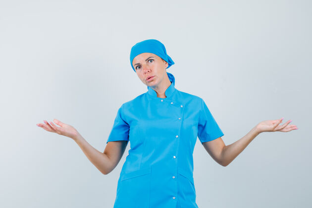 成人穿着蓝色制服的女医生表现出无助的姿态 看上去很困惑前视图护士诊所手势