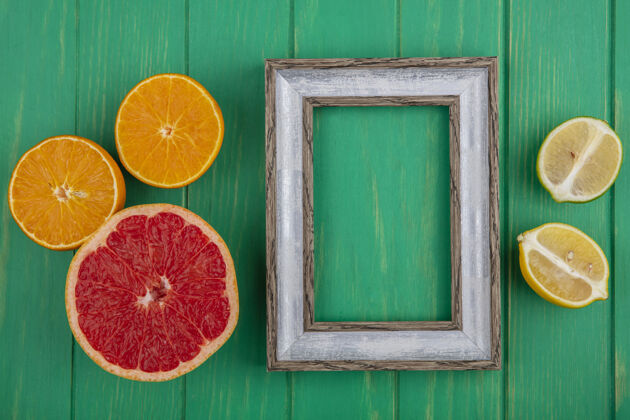 复制顶视图复制空间灰色框架 绿色背景上有一半葡萄柚 柠檬和橙子绿色橙色墙