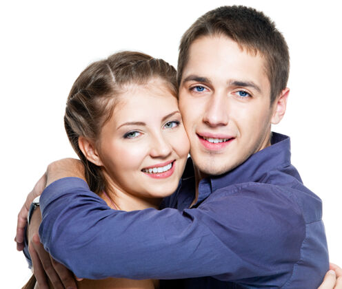 牙齿拥抱年轻幸福美丽夫妇的画像-白墙在一起休闲深情