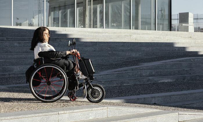 残疾侧视图的妇女坐在轮椅上的街道与复制空间户外条件残障
