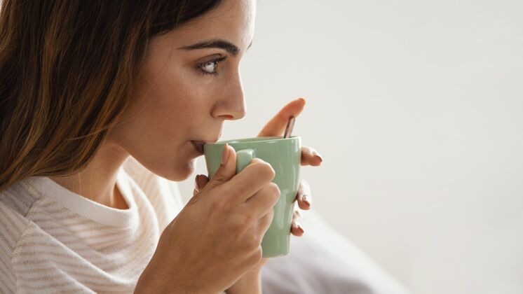 女人女人在床上喝咖啡的侧视图 有复印空间度假室内咖啡