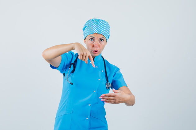 女人女医生指着一件假装穿着蓝色制服的东西 脸上露出惊讶的表情病人惊讶站着
