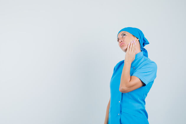 诊断穿着蓝色制服的女医生抚摸着脸颊上的皮肤 看上去很体贴 前视图脸颊诊所肖像