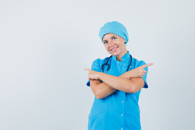 妇女穿着蓝色制服的女医生指着别处 看上去很高兴 正对着前方工作人员疾病年轻人