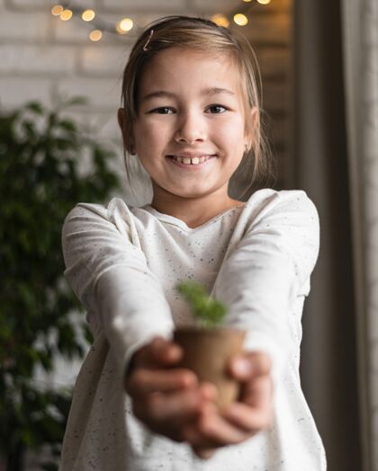 生物笑眯眯的小女孩在家拿着花盆里的植物自然庭院园艺