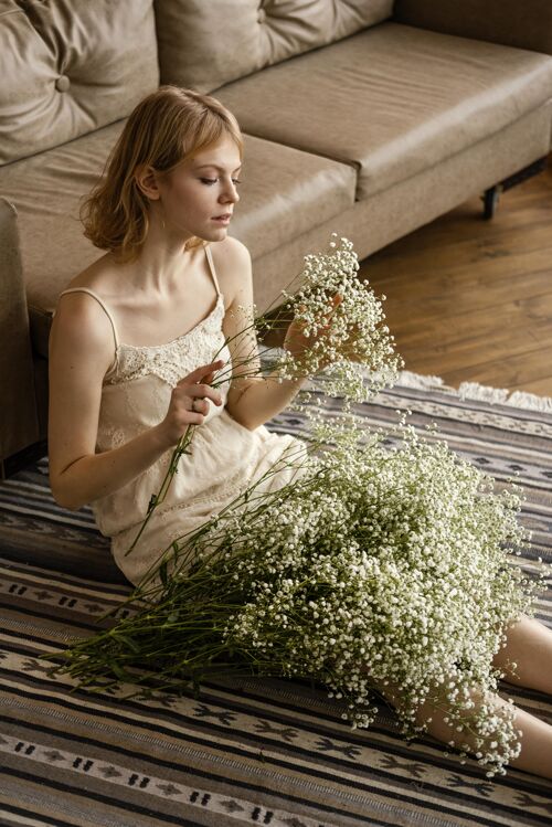 精致坐在沙发边捧着春花的迷人女人年轻春天开花