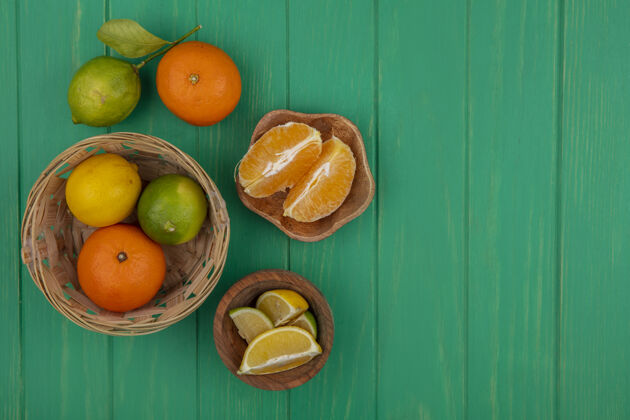 太空顶视图复制空间剥皮橙色切片在一个碗与橙色石灰和柠檬在一个绿色的背景篮子视图果皮复制