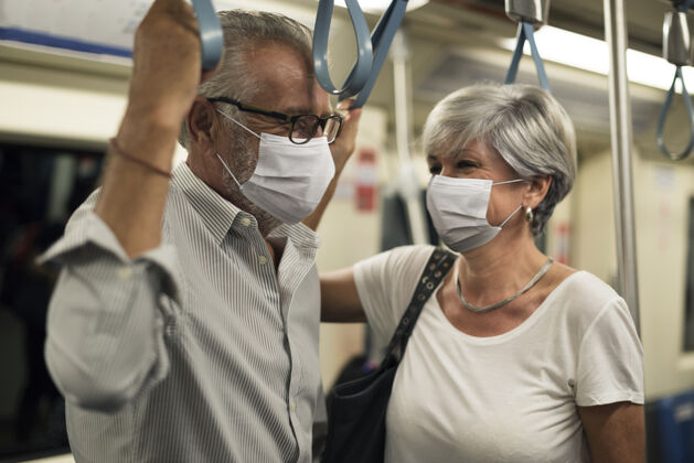 站一对戴着口罩的情侣在新常态的火车上防护关系老人