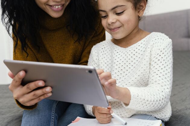 年轻少女帮妹妹使用平板电脑上网上学网络知识女孩